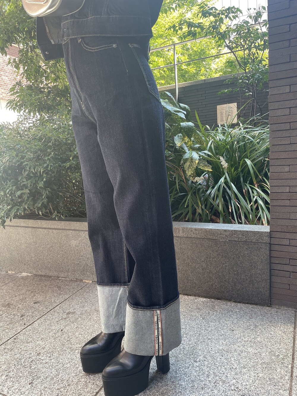 ブラック系のキャミソール、ブルー系のデニムジャケット、ブルー系のデニムパンツを着用したレディースの秋コーディネートの5枚目の写真