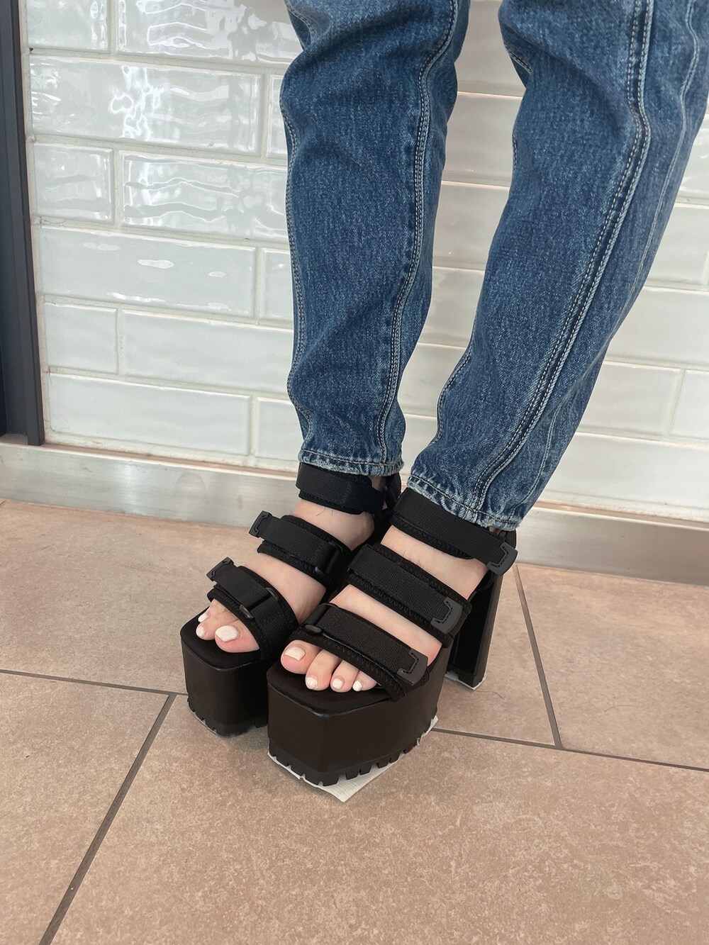 ブルー系のデニムパンツ、ブラック系のハンドバッグ、ブラック系のサンダルを着用したレディースの春コーディネートの7枚目の写真