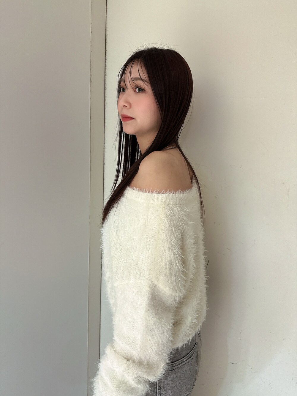 ホワイト系のニット/セーター、グレー系のデニムパンツ、ブラック系のブーツを着用したレディースの冬コーディネートの5枚目の写真