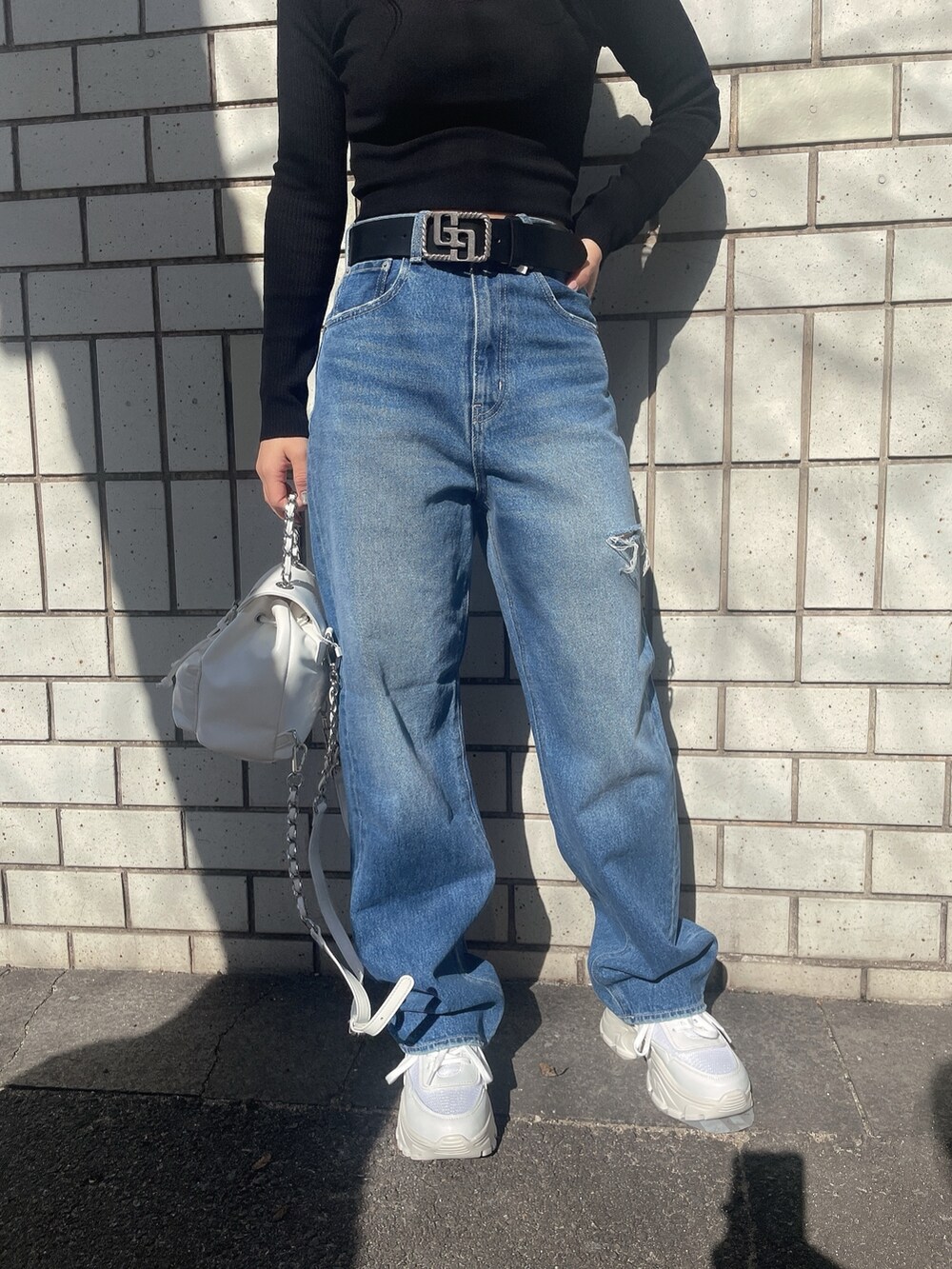 ブラック系のニット/セーター、ホワイト系のバックパック/リュック、ブルー系のデニムパンツを着用したレディースの冬コーディネートの6枚目の写真