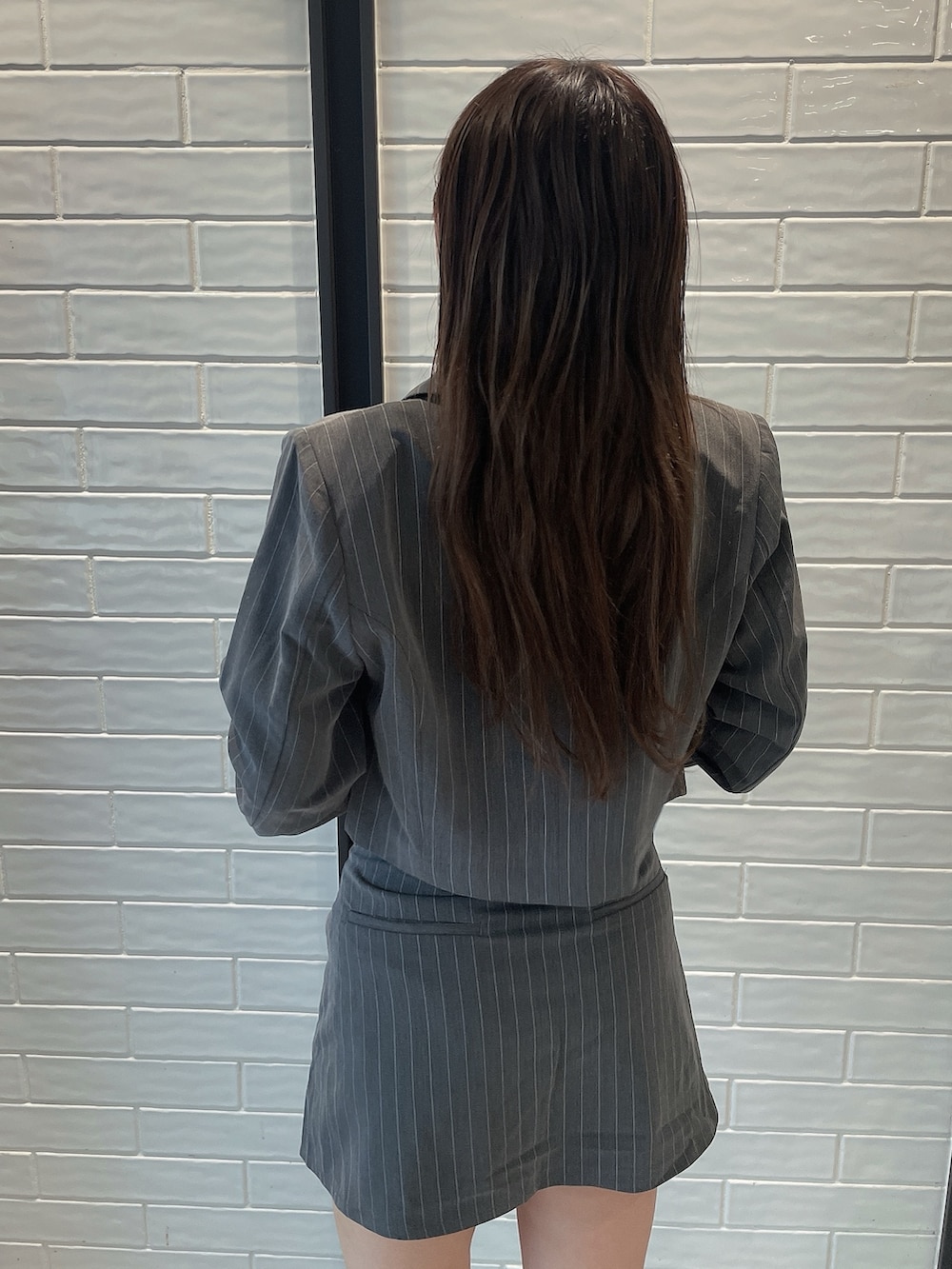 グレー系のスカート、ブラック系のブーツ、グレー系のテーラードジャケットを着用したレディースの夏コーディネートの6枚目の写真