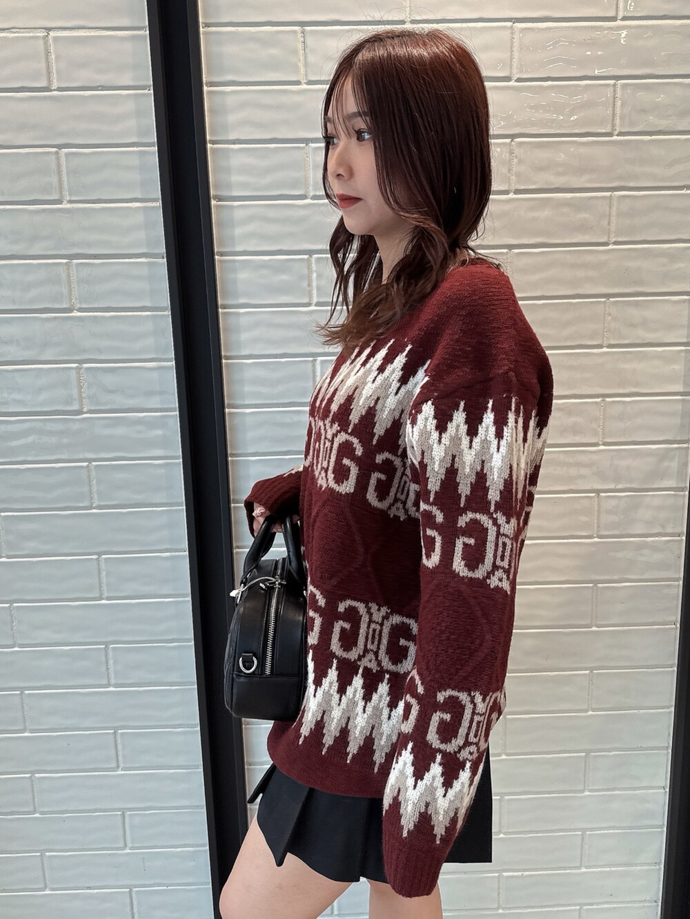 レッド系のニット/セーター、ブラック系のスカート、ブラック系のハンドバッグを着用したレディースの冬コーディネートの5枚目の写真