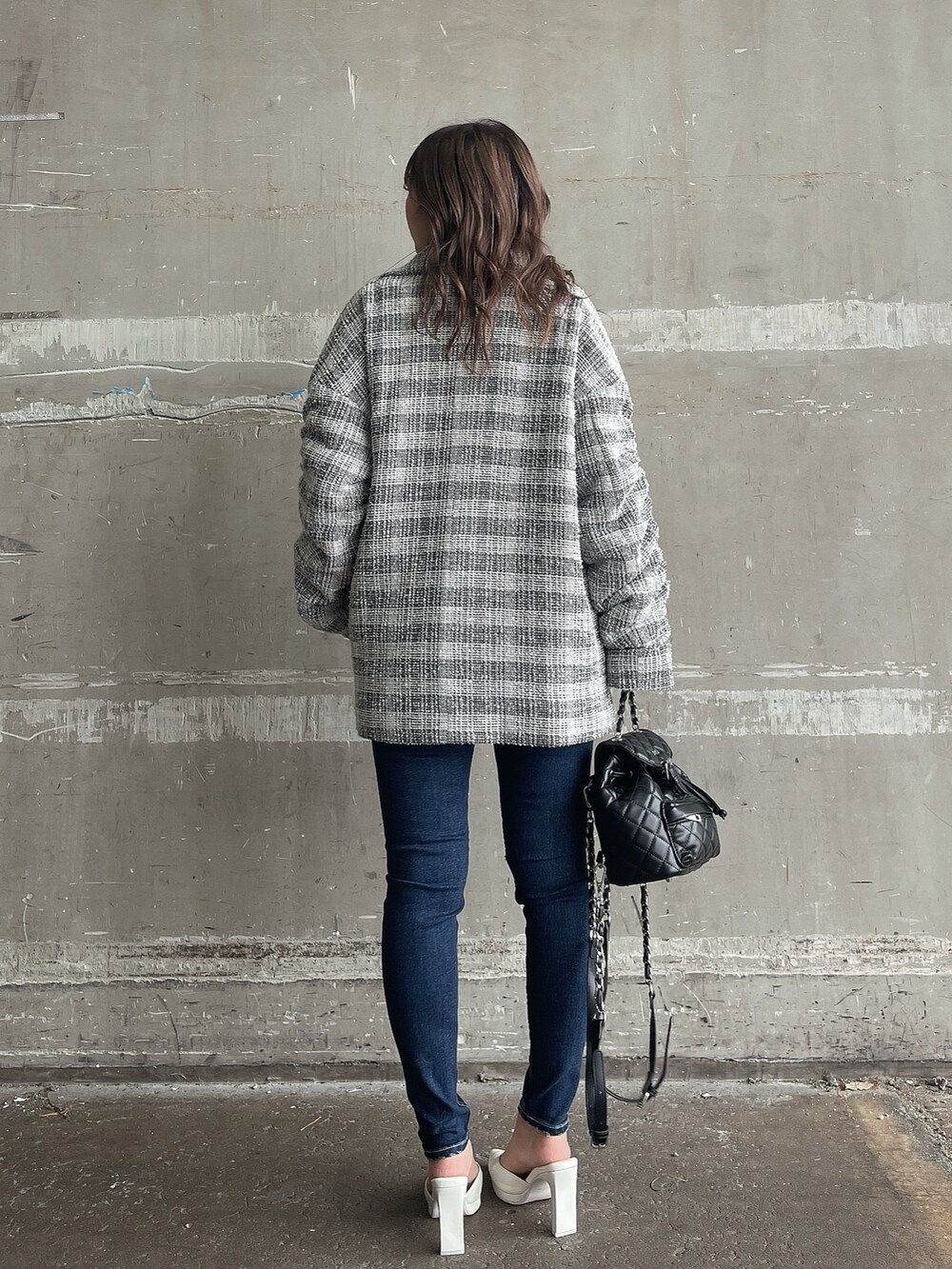 ブラック系のニット/セーター、ブラック系のチェスターコート、ブルー系のデニムパンツを着用したレディースの冬コーディネートの2枚目の写真