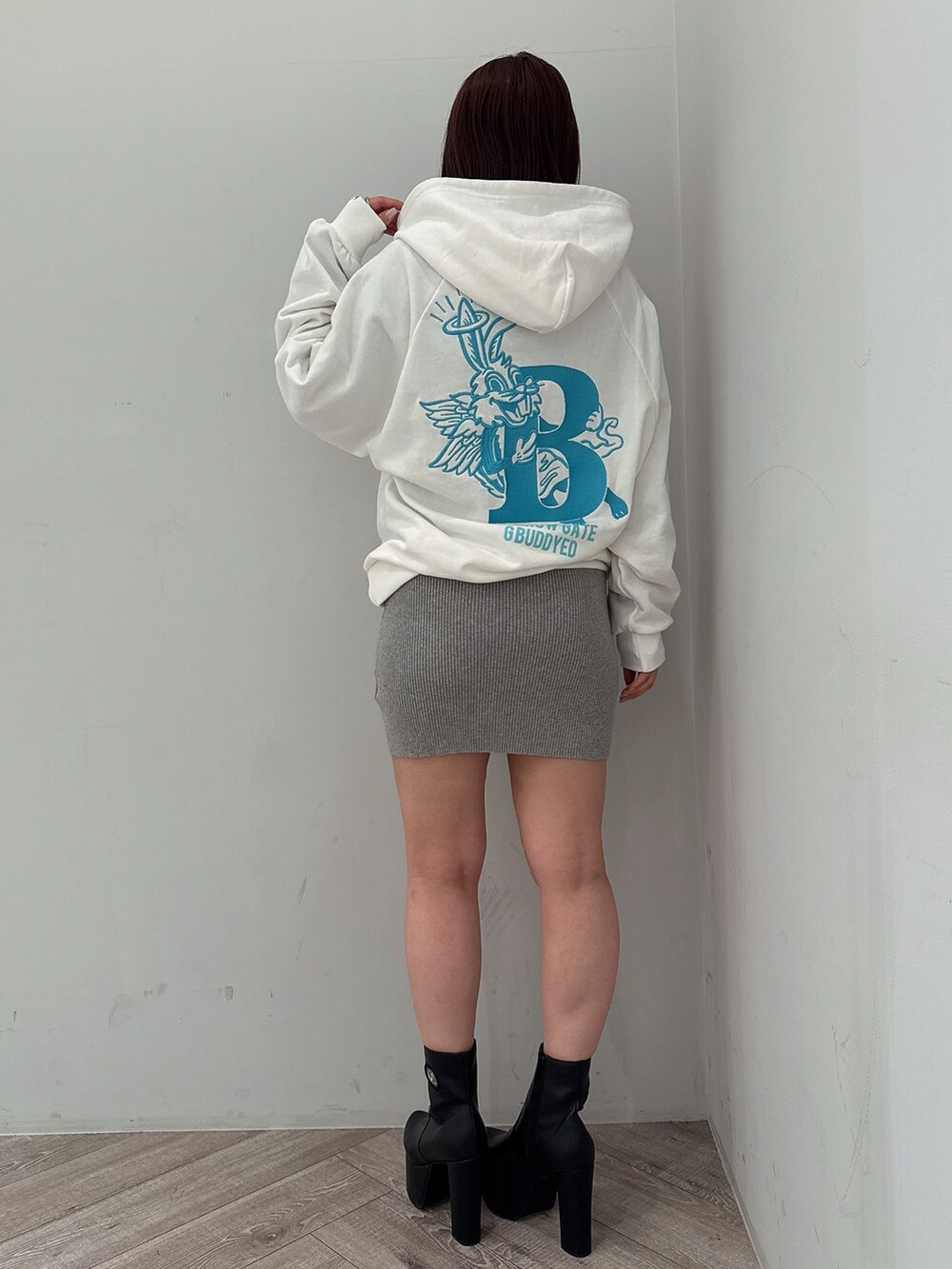 グレー系のワンピース、ホワイト系のパーカー、ブラック系のブーツを着用したレディースの冬コーディネートの3枚目の写真