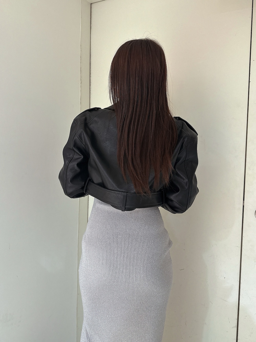 シルバー系のワンピース、ブラック系のライダースジャケット、ブラック系のブーツを着用したレディースの冬コーディネートの6枚目の写真