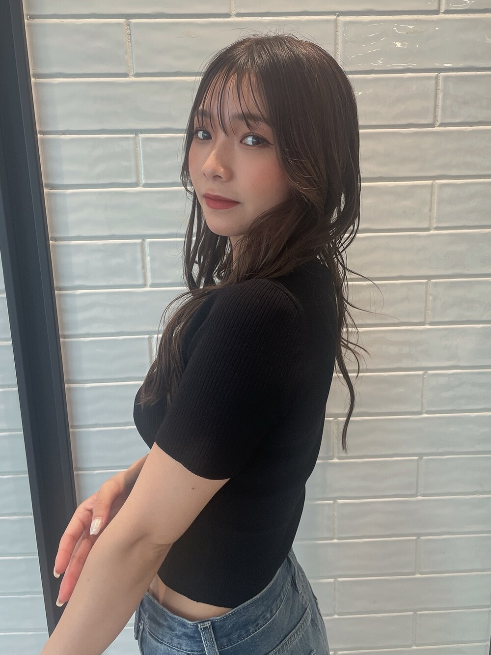 ブラック系のニット/セーター、ブラック系のサンダル、ブルー系のデニムパンツを着用したレディースの夏コーディネートの5枚目の写真