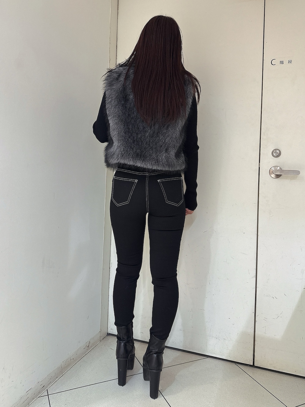 ブラック系のニット/セーター、ブラック系のデニムパンツ、ブラック系のブーツを着用したレディースの秋コーディネートの3枚目の写真