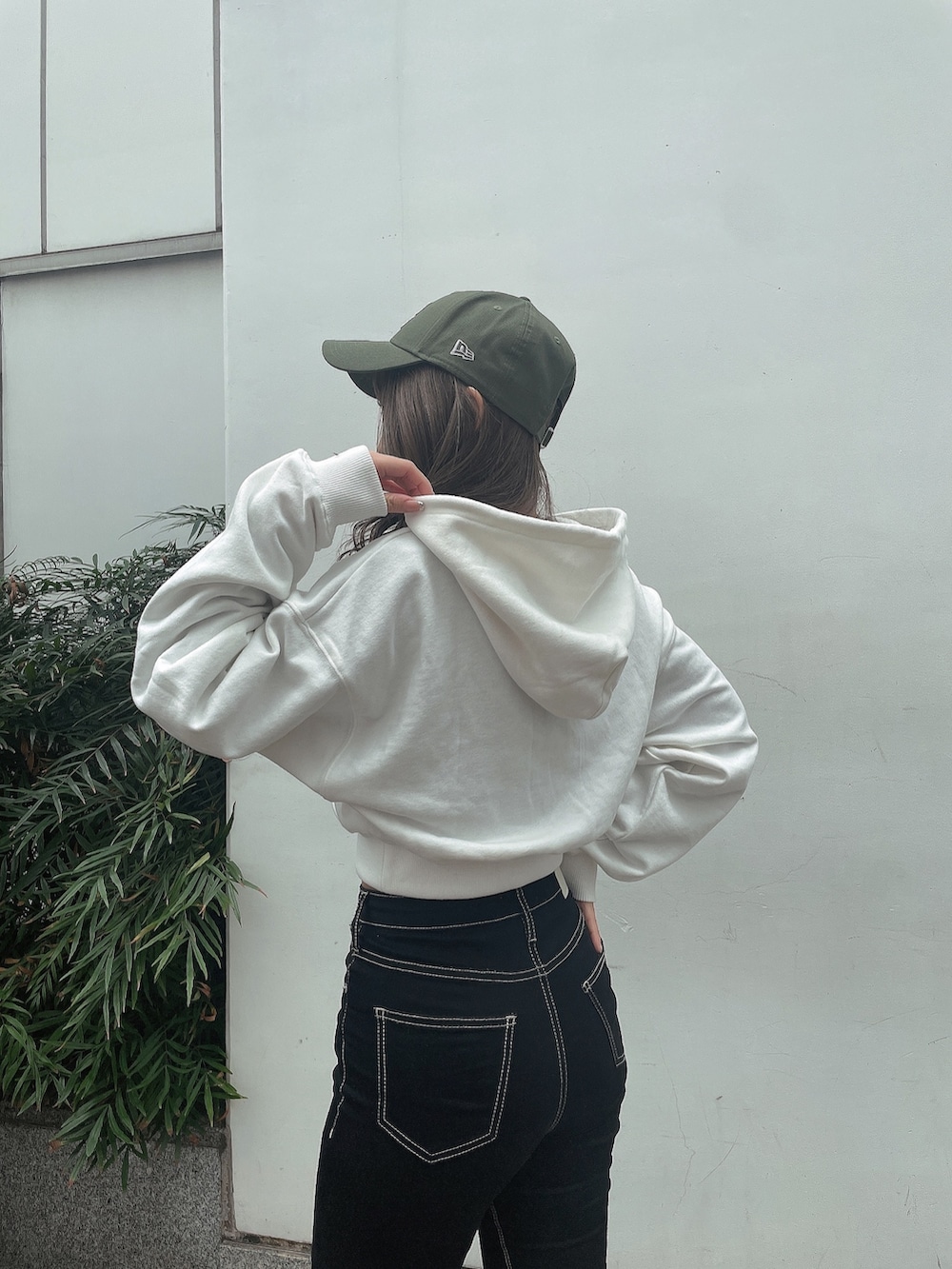 ホワイト系のパーカー、ブラック系のデニムパンツ、ブラック系のブーツを着用したレディースの冬コーディネートの5枚目の写真