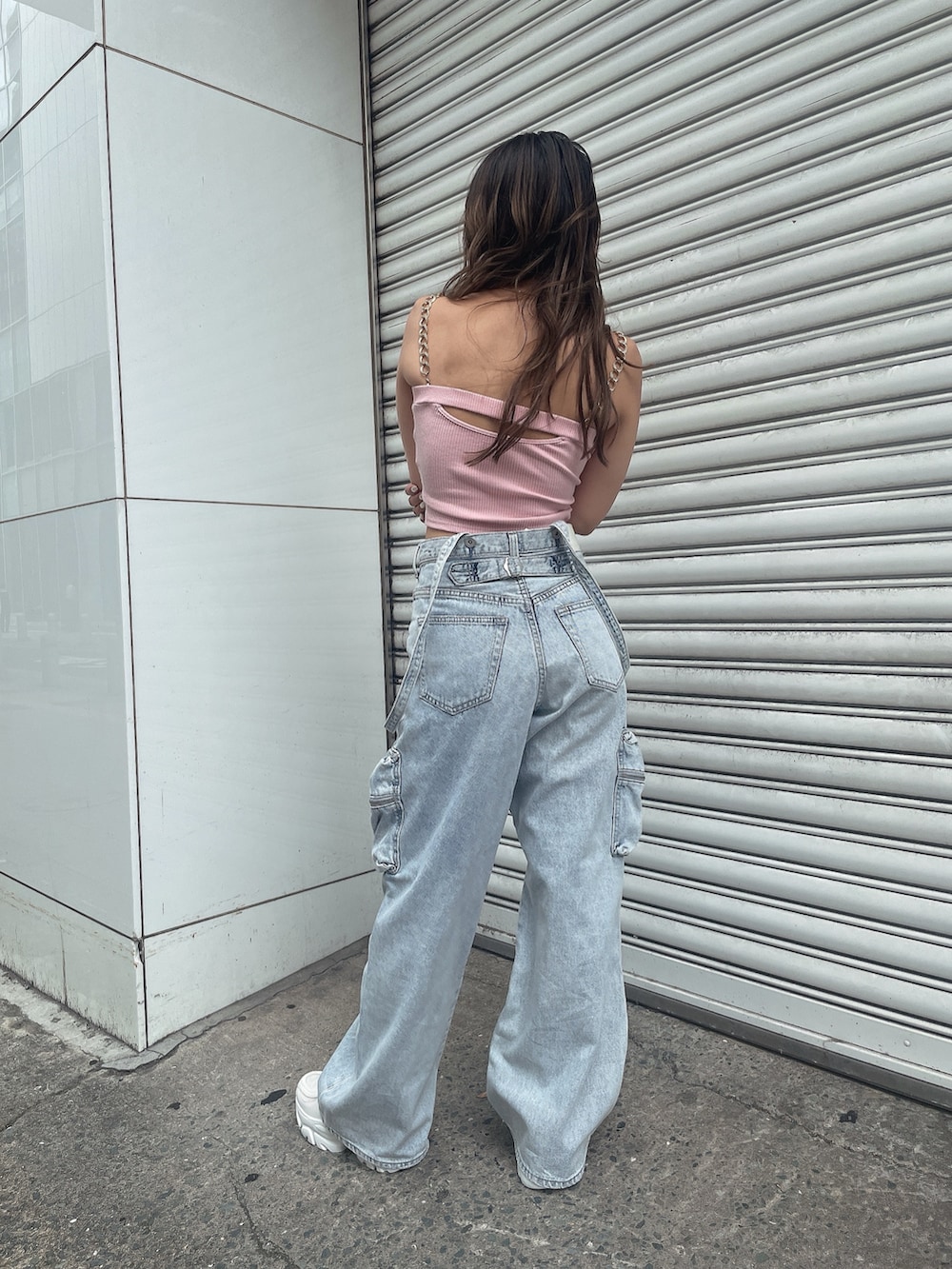 ピンク系のキャミソール、ブルー系のデニムパンツ、ホワイト系のスニーカーを着用したレディースの夏コーディネートの3枚目の写真