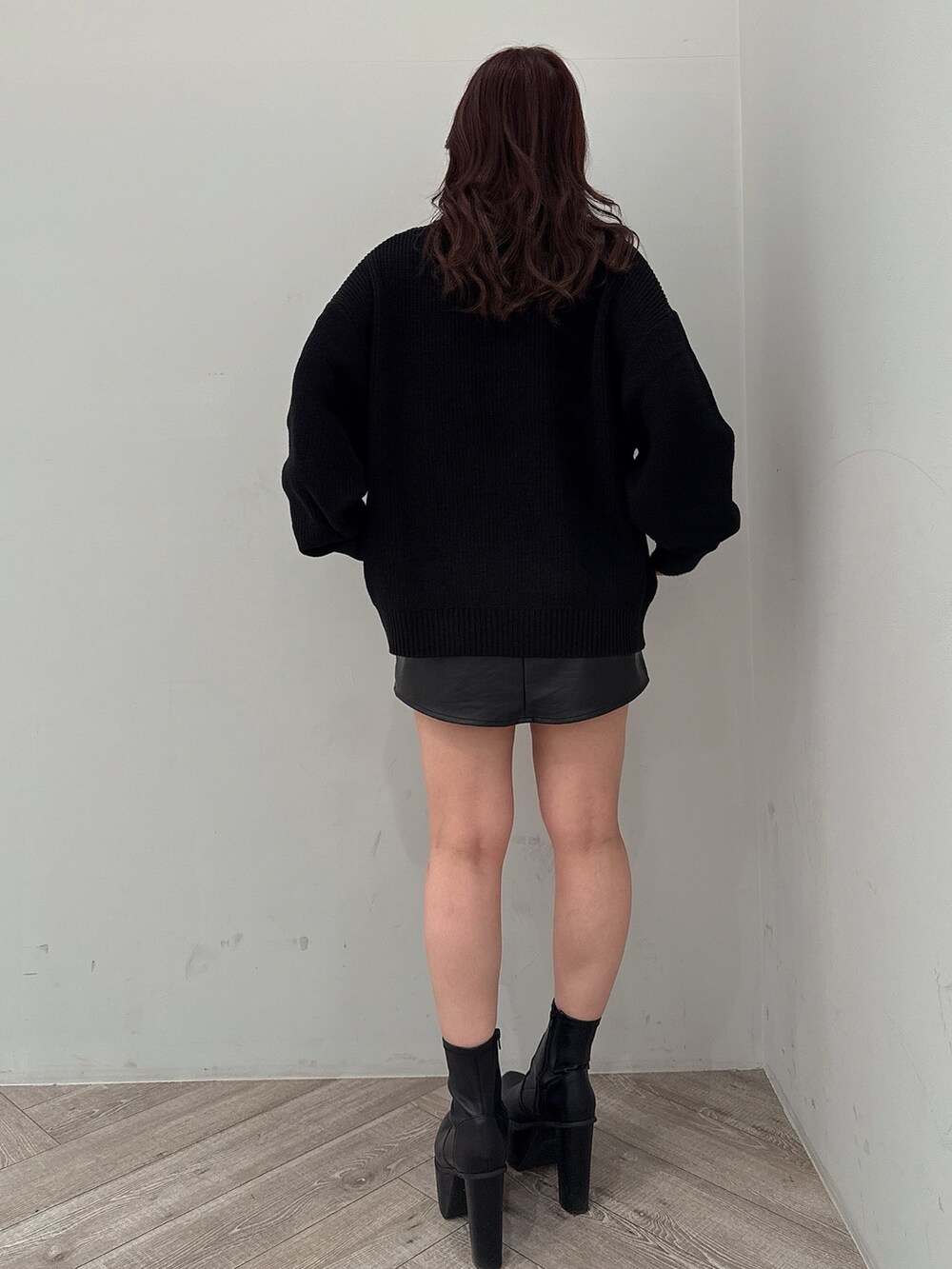 ブラック系のスカート、ブラック系のニット/セーター、ブラック系のブーツを着用したレディースの冬コーディネートの3枚目の写真