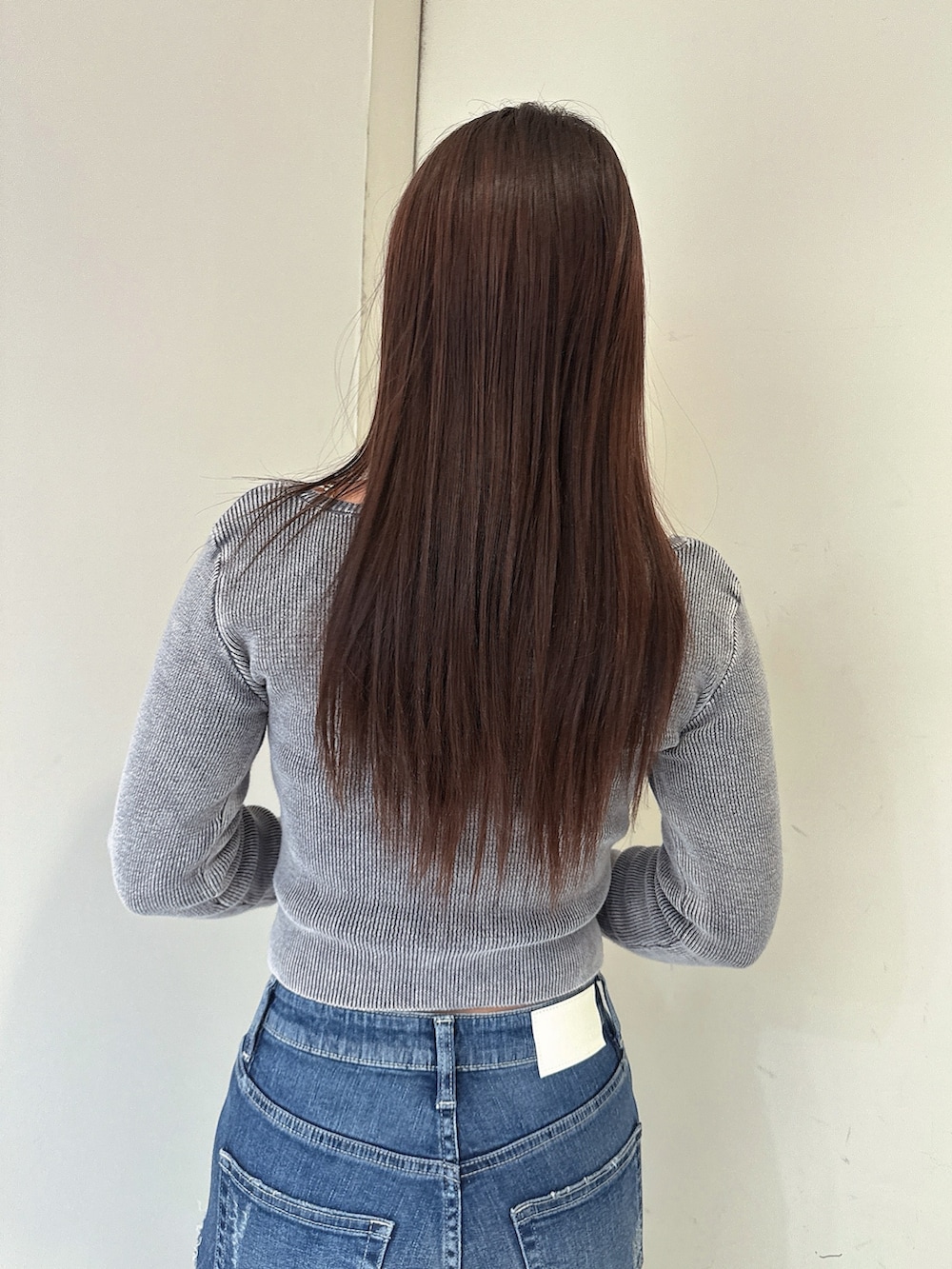ブラック系のニット/セーター、ブルー系のデニムパンツ、ブラック系のサンダルを着用したレディースの春コーディネートの6枚目の写真
