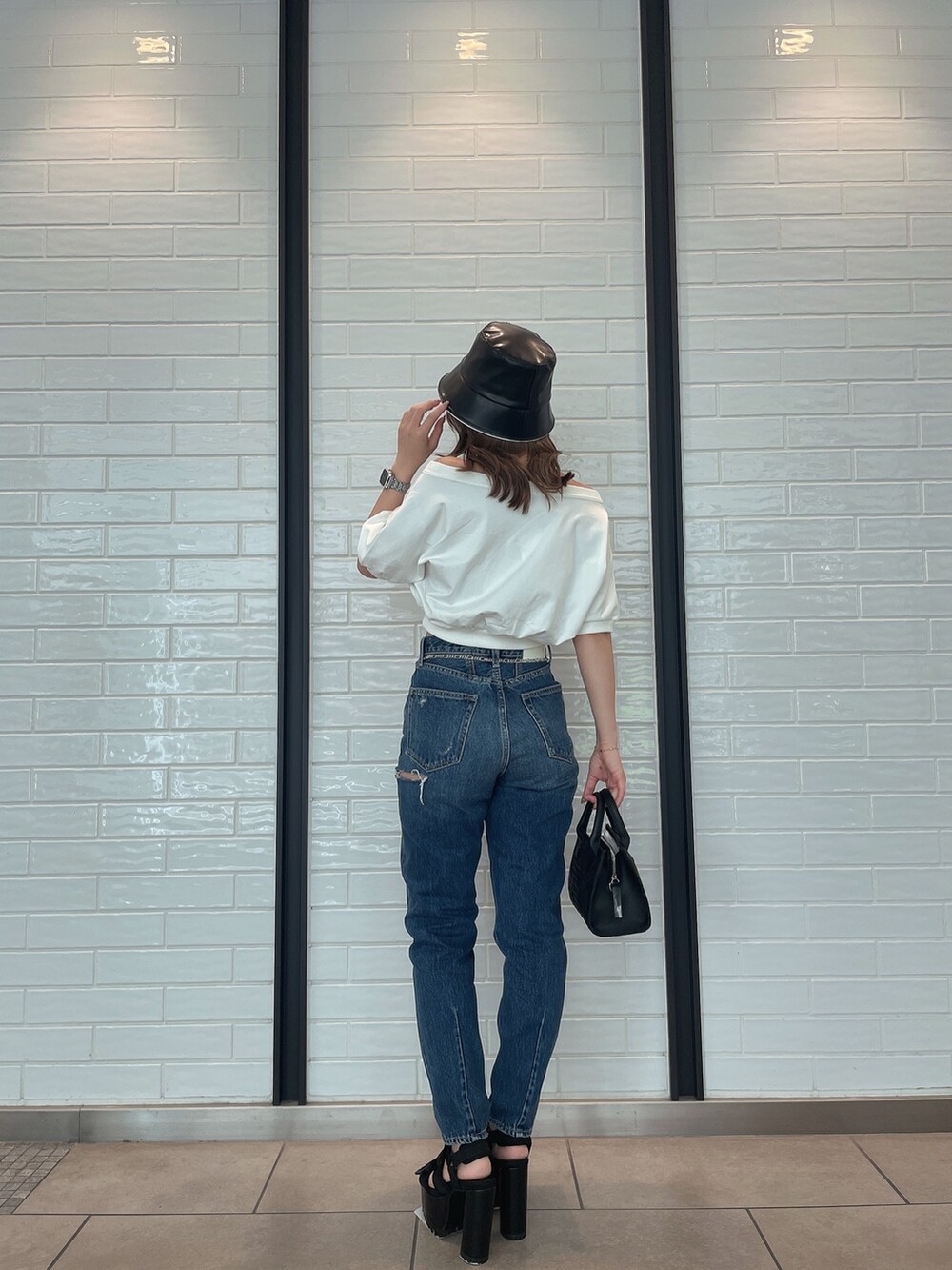 ブルー系のデニムパンツ、ブラック系のハンドバッグ、ブラック系のサンダルを着用したレディースの春コーディネートの2枚目の写真