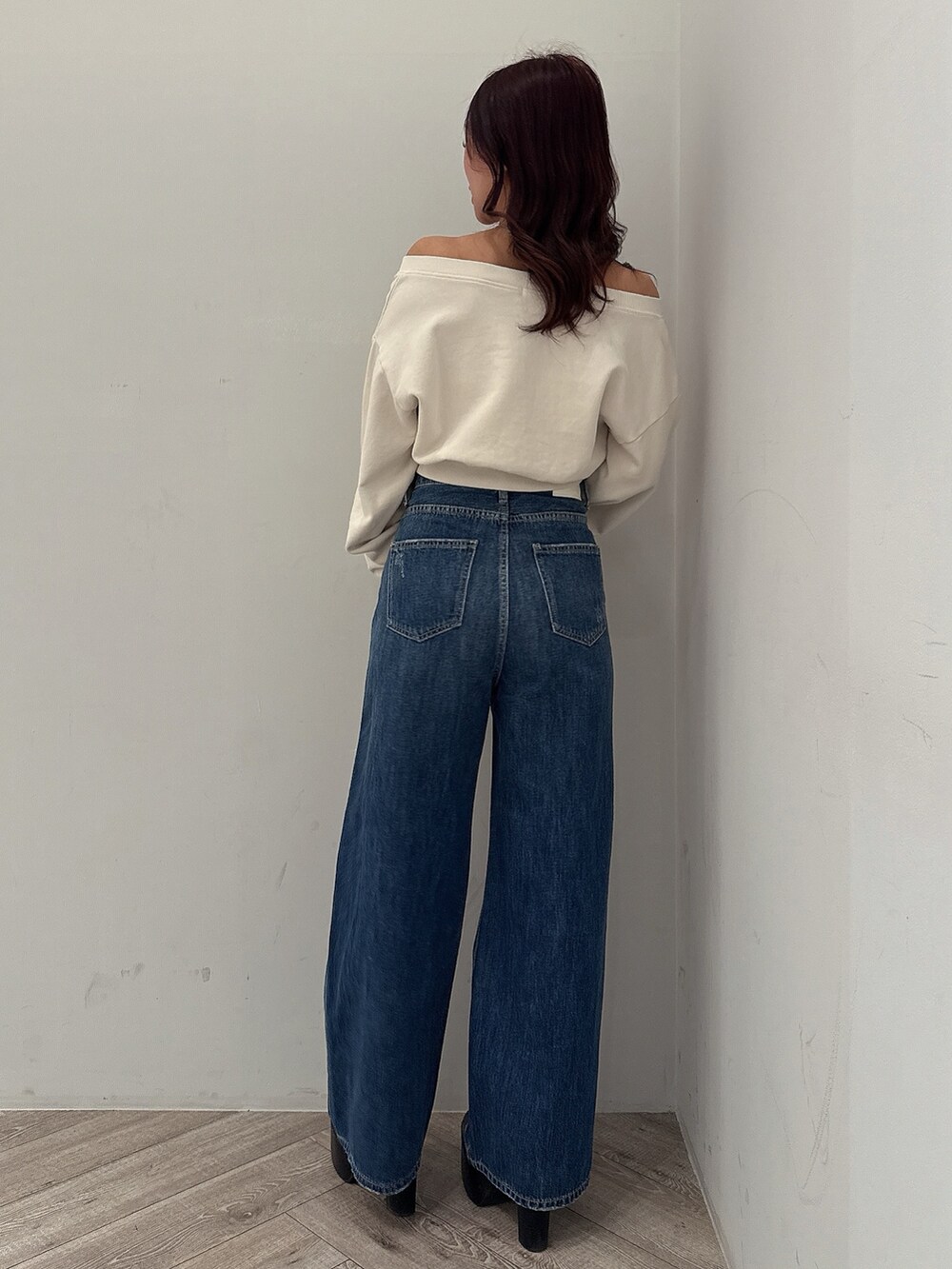 ホワイト系のスウェット、ブルー系のデニムパンツ、ブラック系のブーツを着用したレディースの秋コーディネートの3枚目の写真