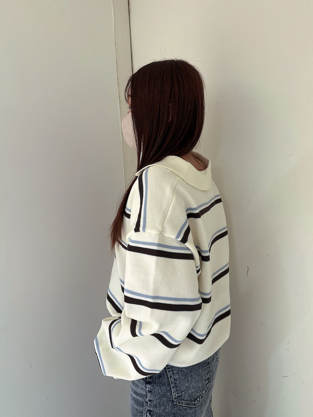 ブラック系のブーツ、ホワイト系のニット/セーター、ブルー系のデニムスカートを着用したレディースの冬コーディネートの5枚目の写真