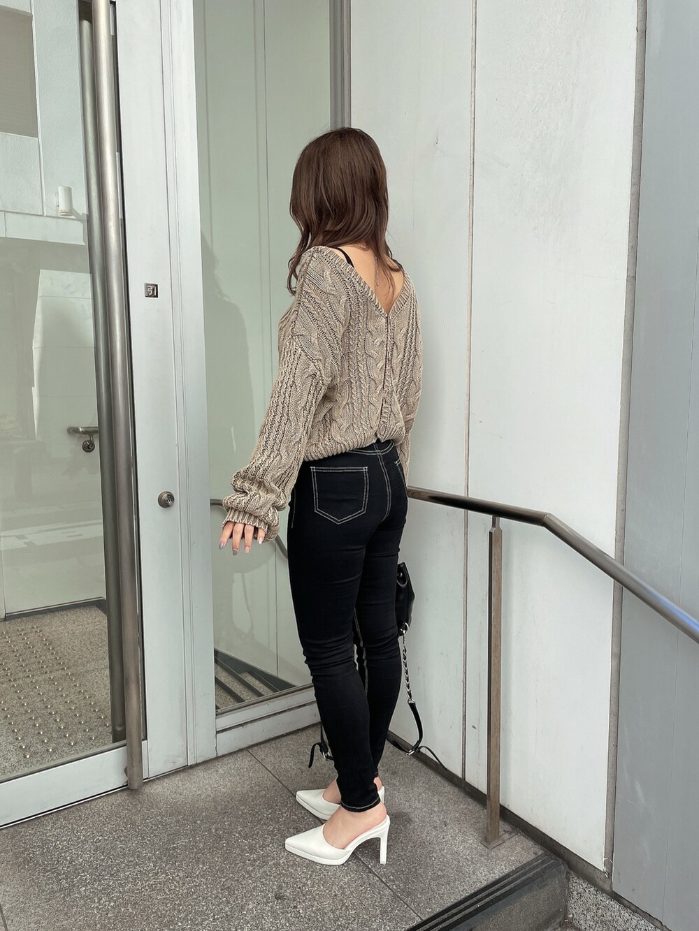 ベージュ系のニット/セーター、ブラック系のキャミソール、ブラック系のデニムパンツを着用したレディースの冬コーディネートの3枚目の写真