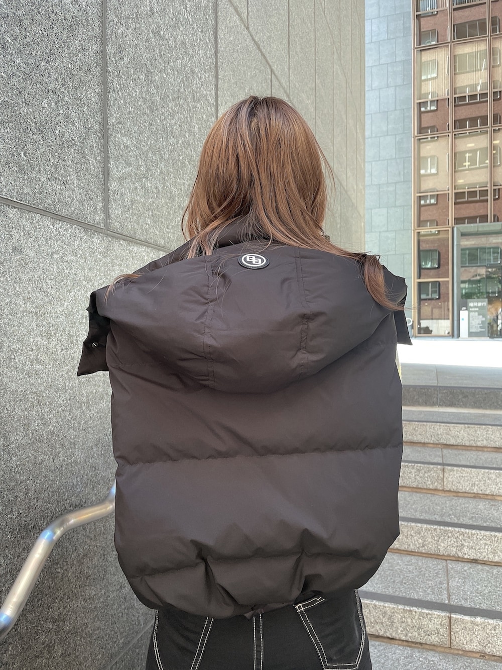 グレー系のニット/セーター、ブラック系のダウンジャケット/コート、ブラック系のデニムパンツを着用したレディースの秋コーディネートの4枚目の写真