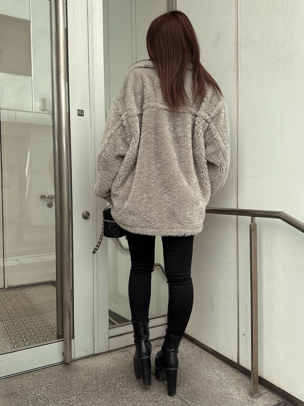 グレー系のブルゾン、ブラック系のデニムパンツ、ブラック系のブーツを着用したレディースの冬コーディネートの3枚目の写真