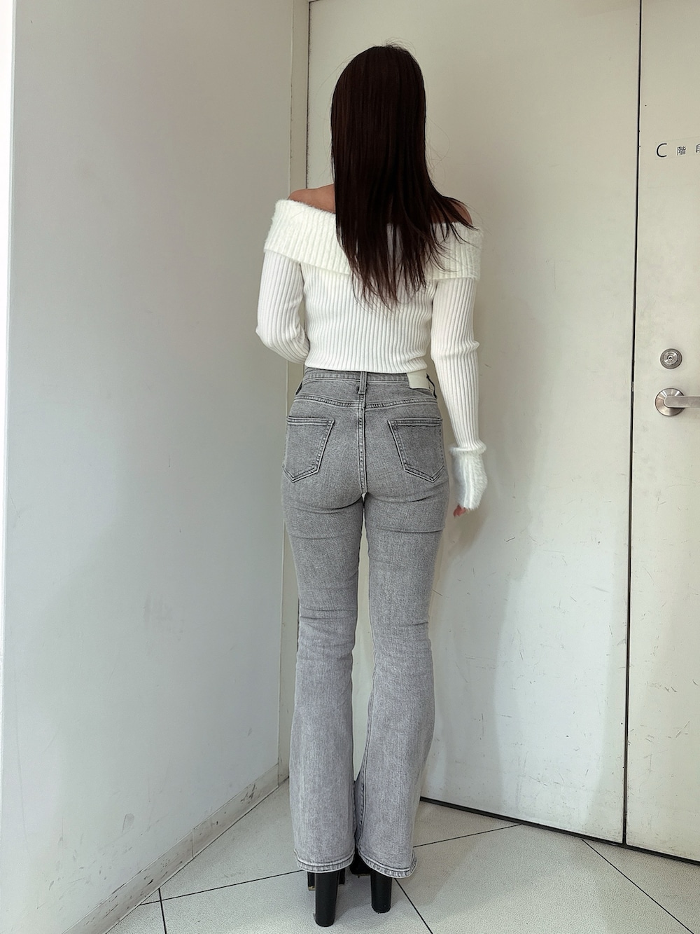 グレー系のデニムパンツ、ブラック系のブーツ、ホワイト系のニット/セーターを着用したレディースの冬コーディネートの3枚目の写真
