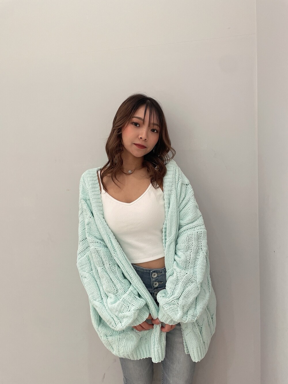 ホワイト系のキャミソール、ブルー系のデニムパンツ、グリーン系のカーディガン/ボレロを着用したレディースの冬コーディネートの4枚目の写真