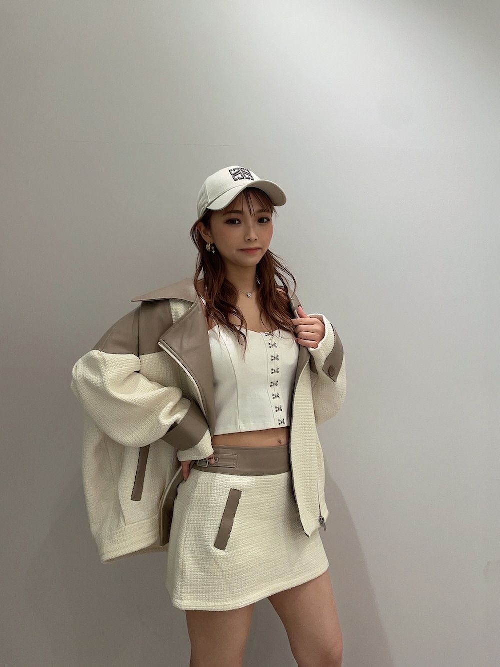 ホワイト系のキャミソール、ホワイト系のライダースジャケット、ホワイト系のスカートを着用したレディースの春コーディネートの4枚目の写真