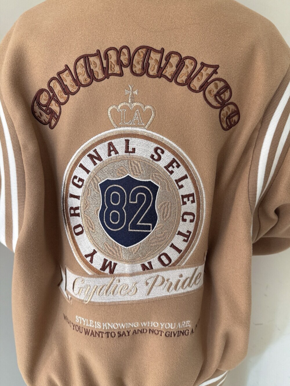 ブラック系のデニムパンツ、ブラック系のニット/セーター、ベージュ系のスタジャンを着用したレディースの秋コーディネートの8枚目の写真