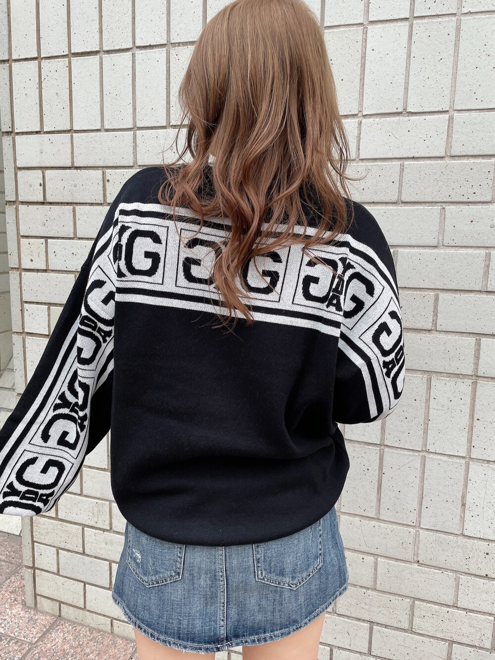 ブラック系のニット/セーター、ブルー系のデニムスカート、ブラック系のハンドバッグを着用したレディースの冬コーディネートの5枚目の写真