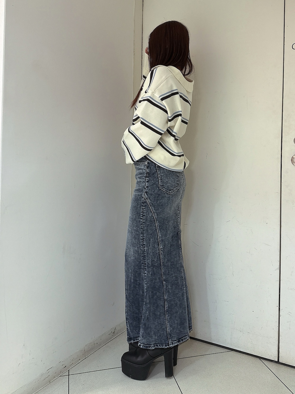 ブラック系のブーツ、ホワイト系のニット/セーター、ブルー系のデニムスカートを着用したレディースの冬コーディネートの2枚目の写真