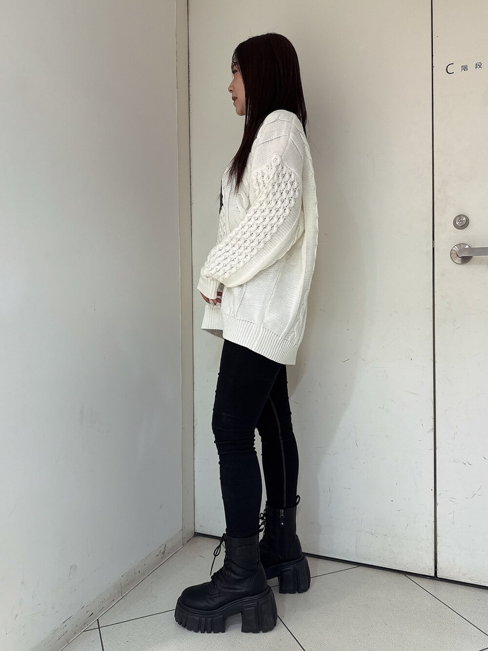 ホワイト系のニット/セーター、ブラック系のデニムパンツ、ブラック系のブーツを着用したレディースの秋コーディネートの2枚目の写真