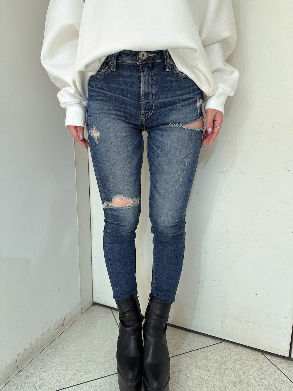 ブルー系のデニムパンツ、ブラック系のブーツ、ホワイト系のスウェットを着用したレディースの冬コーディネートの9枚目の写真