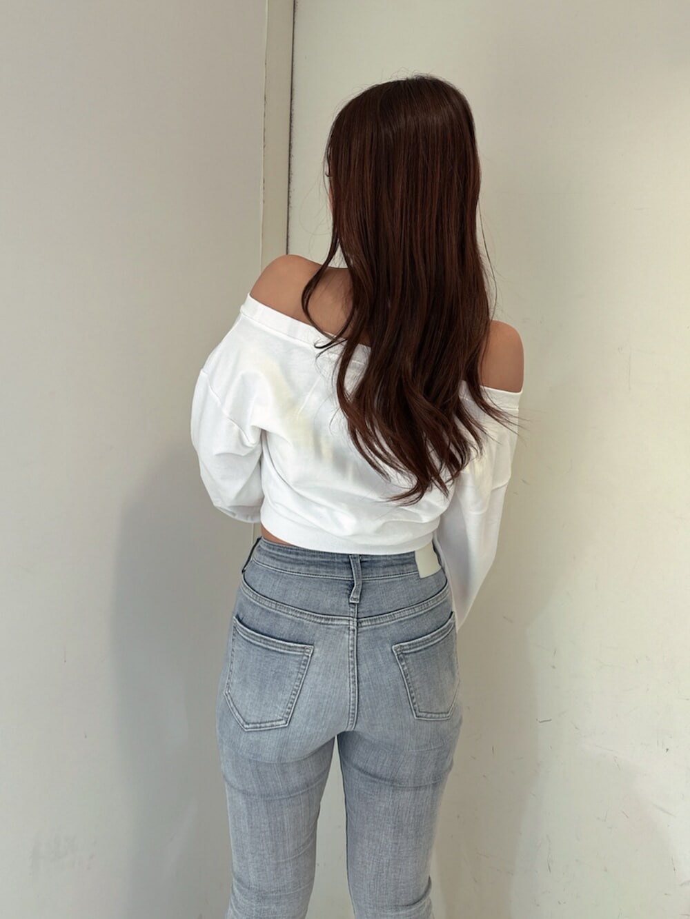 ブルー系のデニムパンツ、ホワイト系のスウェット、ホワイト系のブーツを着用したレディースの夏コーディネートの6枚目の写真