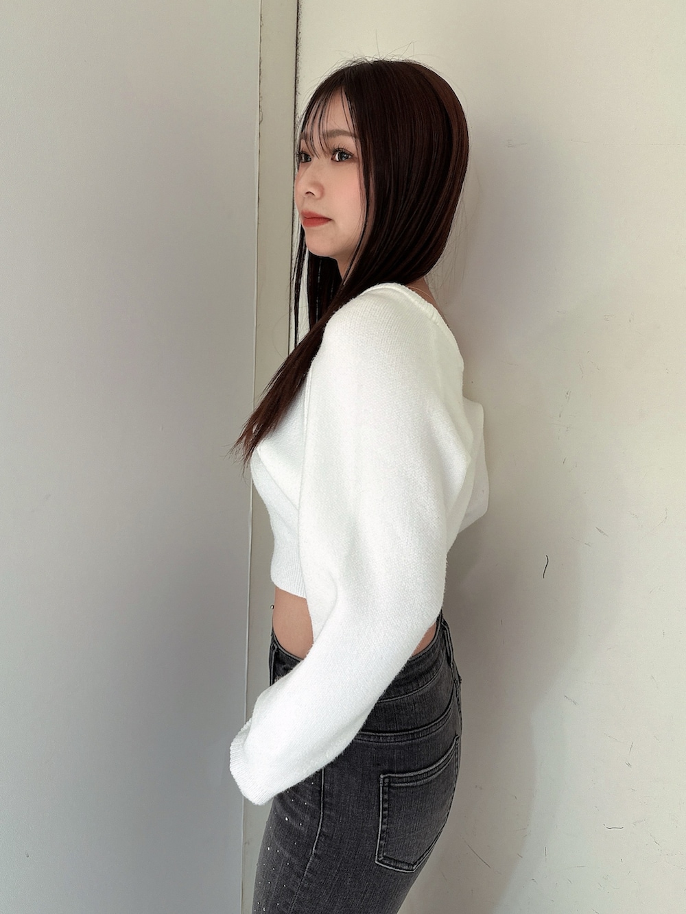 ブラック系のデニムパンツ、ブラック系のブーツ、ホワイト系のニット/セーターを着用したレディースの冬コーディネートの5枚目の写真