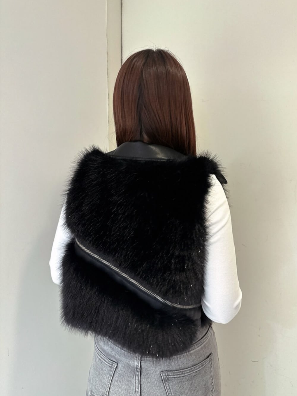 グレー系のデニムパンツ、ブラック系のブーツ、ブラック系のベストを着用したレディースの秋コーディネートの6枚目の写真