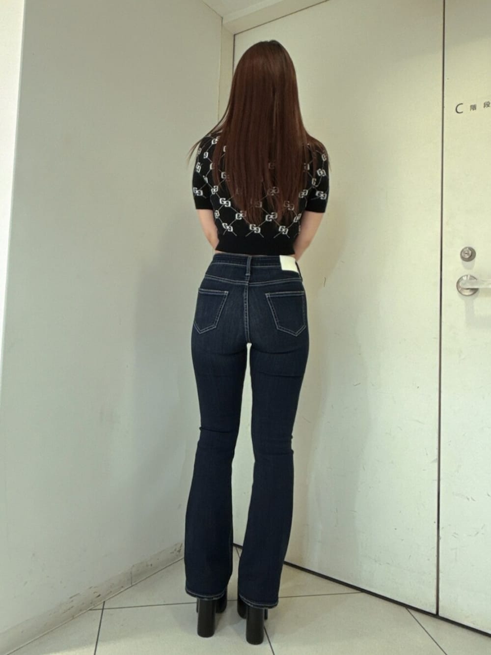 ブルー系のデニムパンツ、ブラック系のニット/セーター、ブラック系のサンダルを着用したレディースの春コーディネートの3枚目の写真