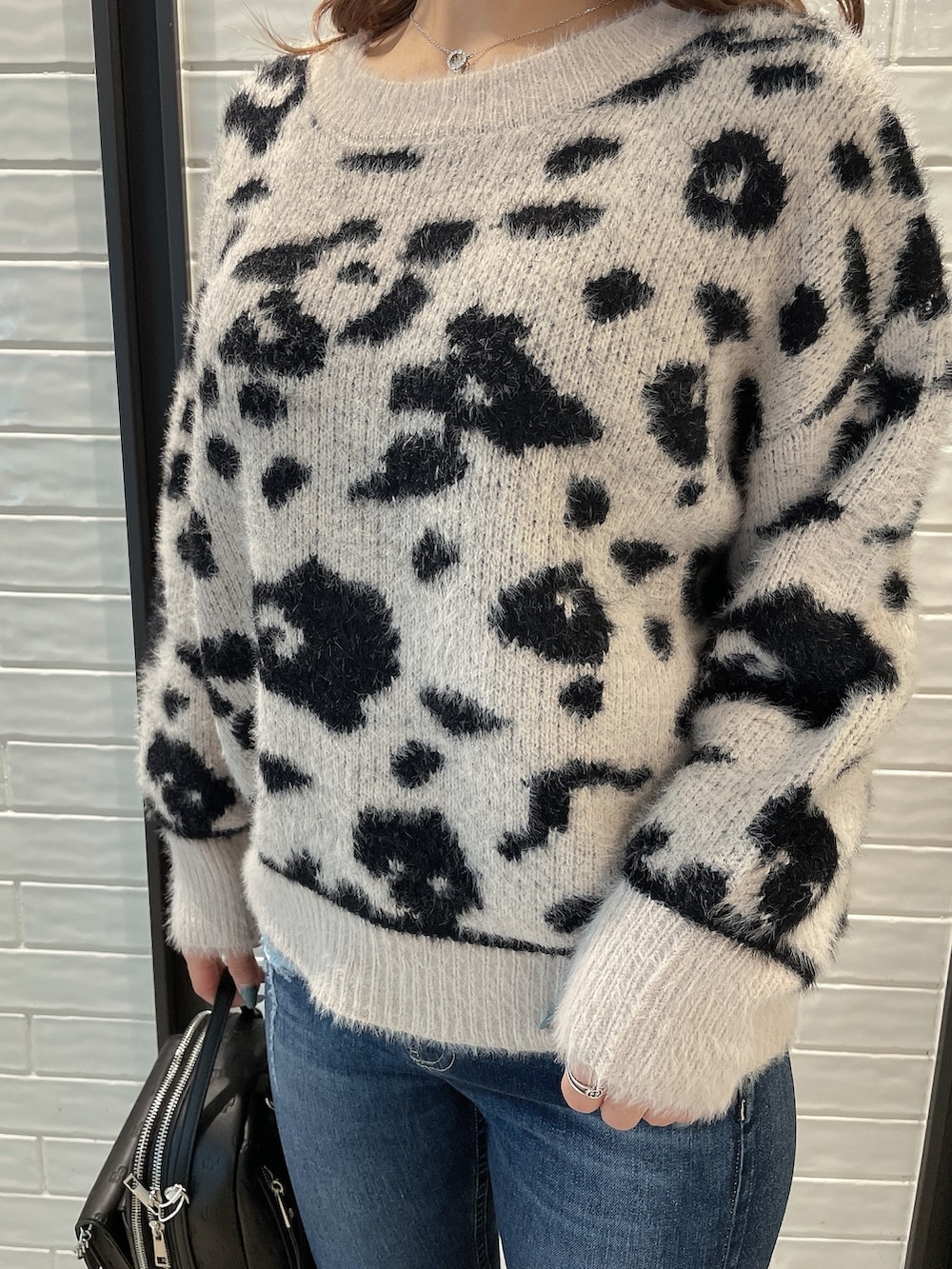 ホワイト系のニット/セーター、ブラック系のバックパック/リュック、ブラック系のパンプスを着用したレディースの冬コーディネートの5枚目の写真