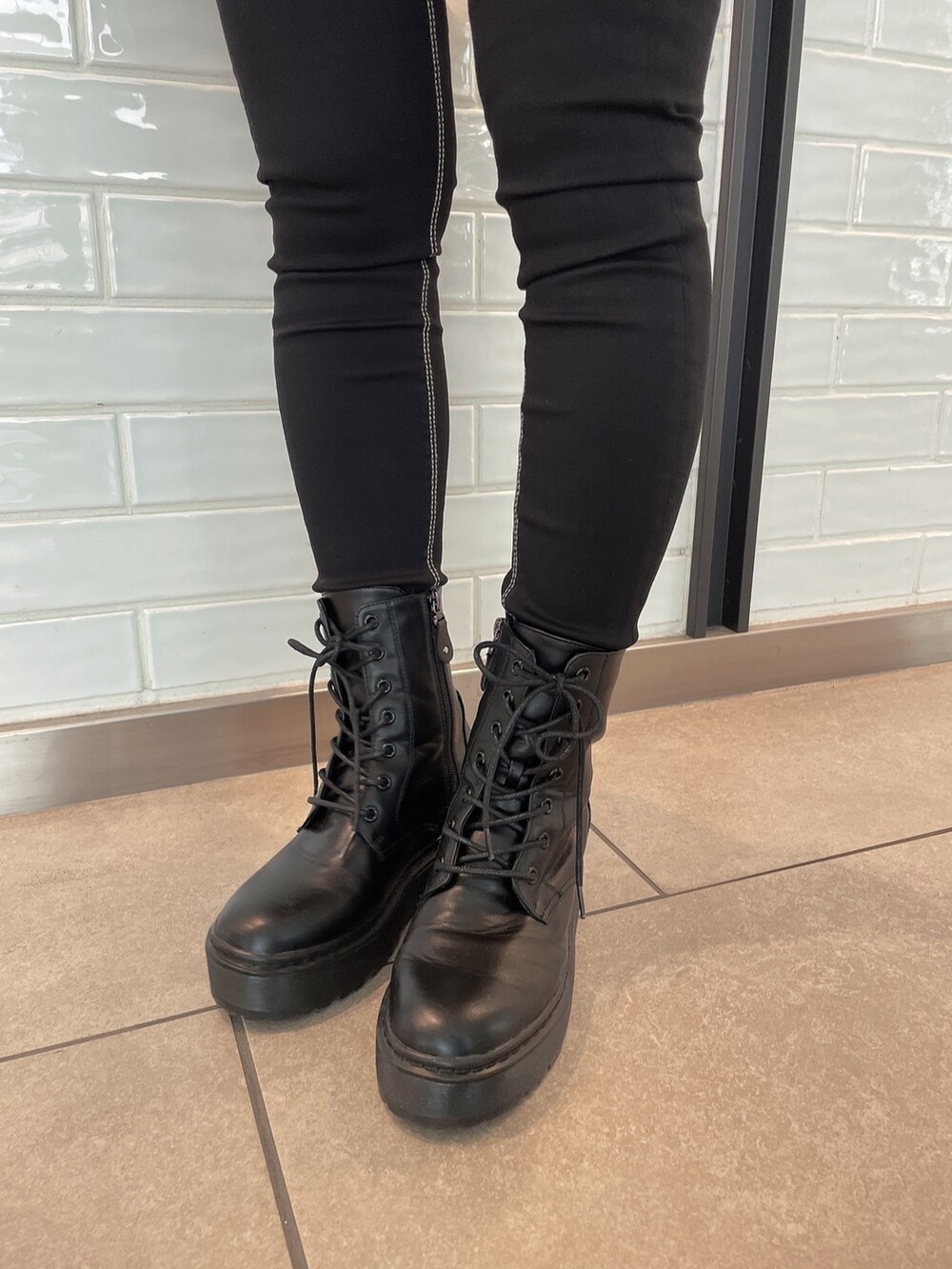 ブラック系のワンピース、ブラック系のデニムパンツ、ブラック系のブーツを着用したレディースの秋コーディネートの9枚目の写真
