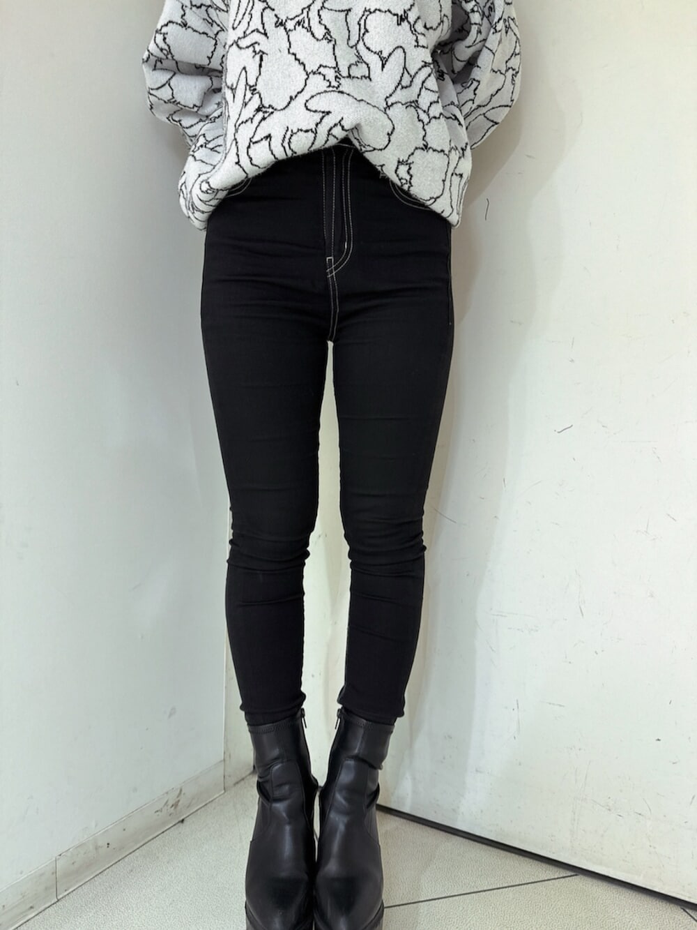 ブラック系のデニムパンツ、ブラック系のブーツ、ホワイト系のニット/セーターを着用したレディースの冬コーディネートの8枚目の写真