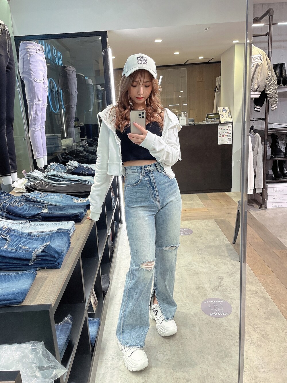 ホワイト系のパーカー、ブラック系のチューブトップ、ブルー系のデニムパンツを着用したレディースの冬コーディネートの2枚目の写真