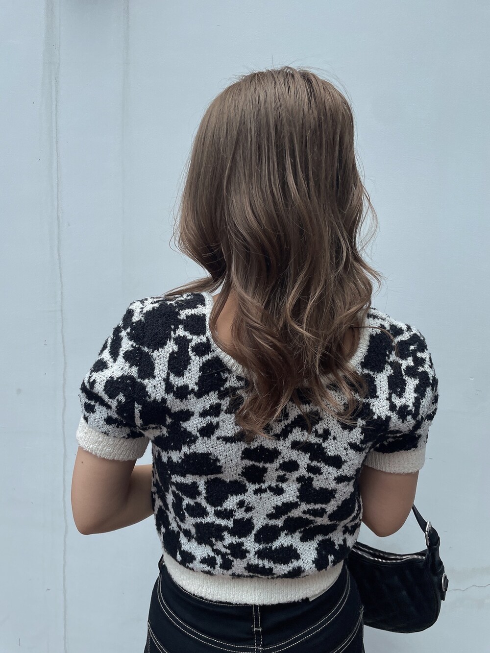 ホワイト系のニット/セーター、ブラック系のデニムパンツ、ブラック系のサンダルを着用したレディースの夏コーディネートの5枚目の写真