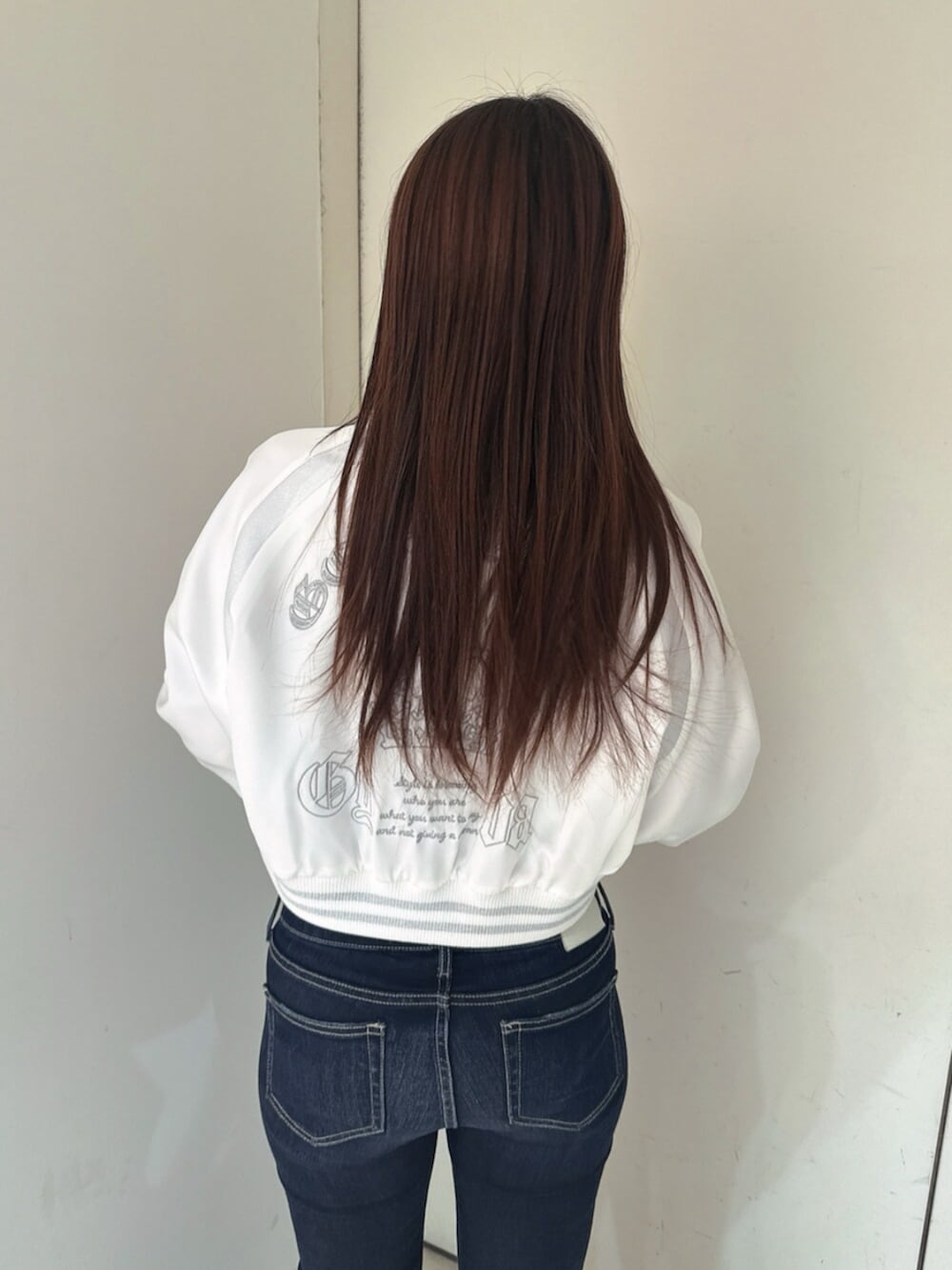 ブルー系のデニムパンツ、ブラック系のサンダル、ホワイト系のブルゾンを着用したレディースの春コーディネートの6枚目の写真