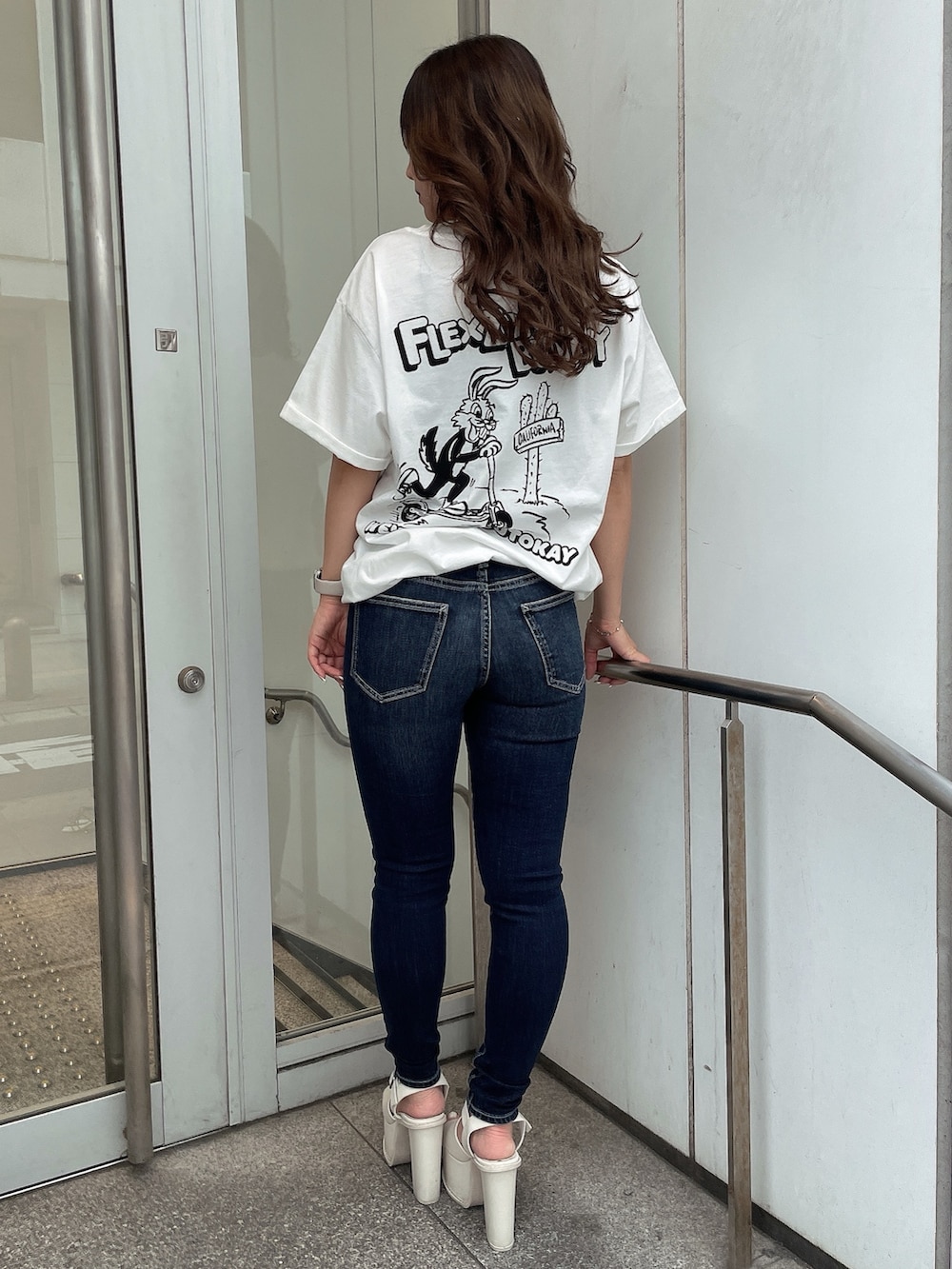 ホワイト系のTシャツ/カットソー、ブルー系のデニムパンツ、ホワイト系のサンダルを着用したレディースの夏コーディネートの3枚目の写真