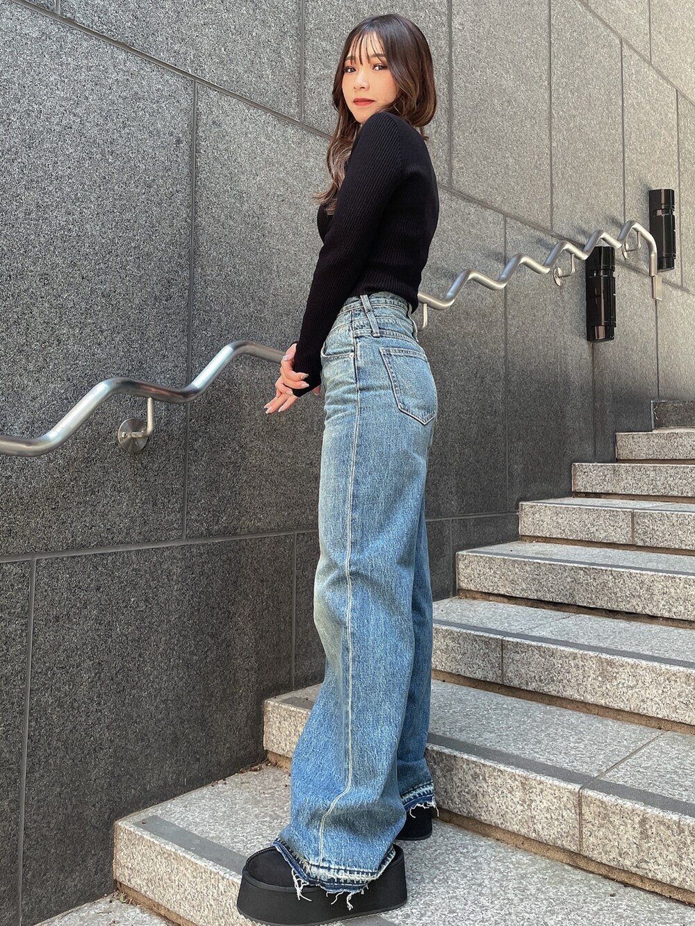 ブラック系のニット/セーター、ブルー系のデニムパンツ、ブラック系のスリッポンを着用したレディースの秋コーディネートの2枚目の写真