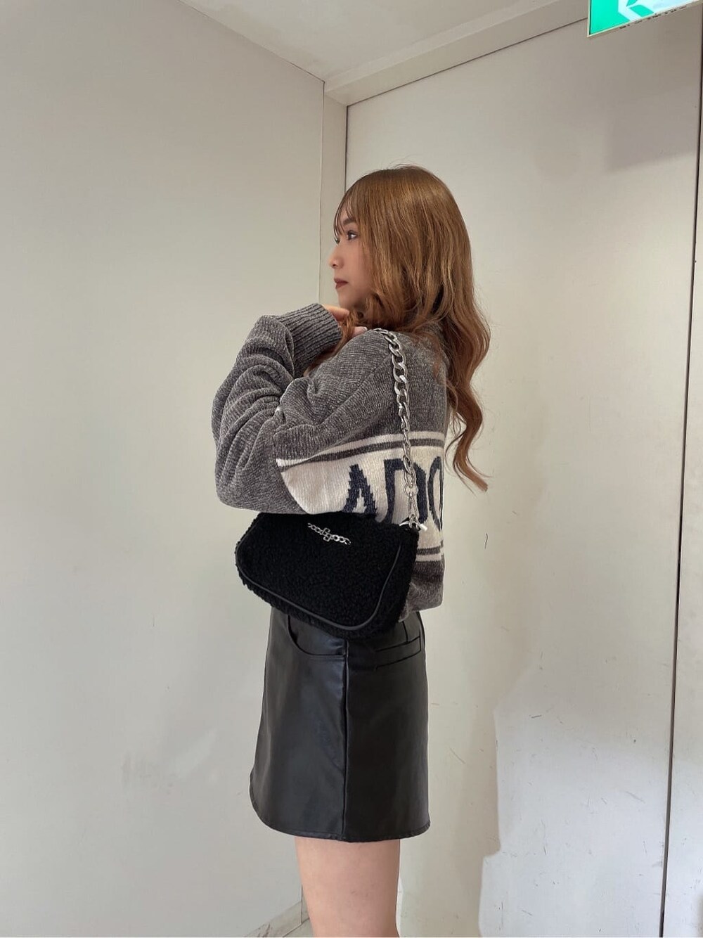 ブラック系のブーツ、グレー系のニット/セーター、ブラック系のハンドバッグを着用したレディースの秋コーディネートの3枚目の写真