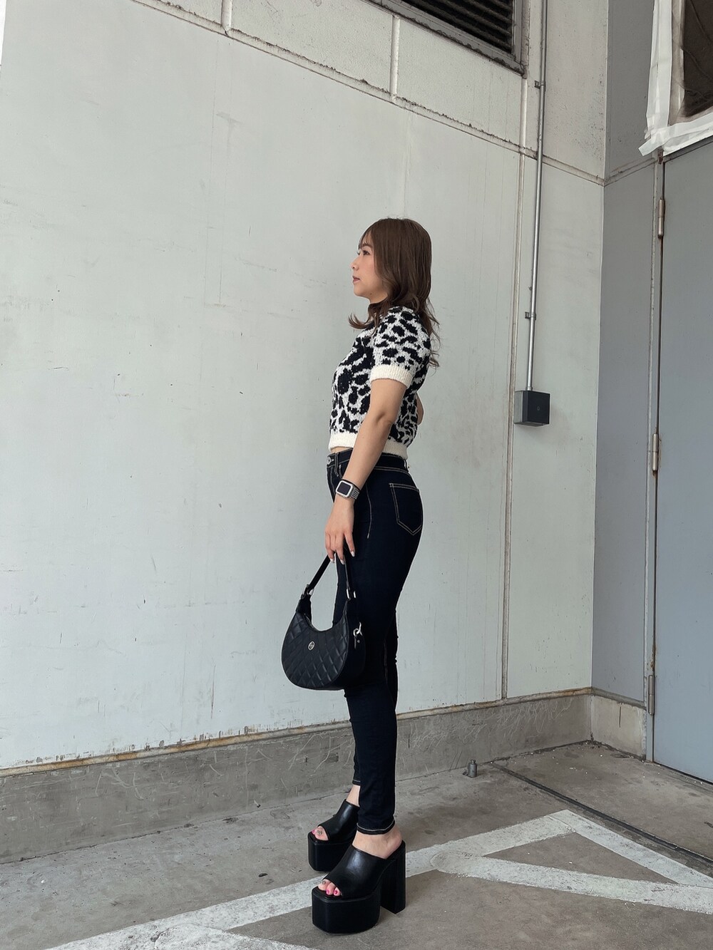 ホワイト系のニット/セーター、ブラック系のデニムパンツ、ブラック系のサンダルを着用したレディースの夏コーディネートの2枚目の写真