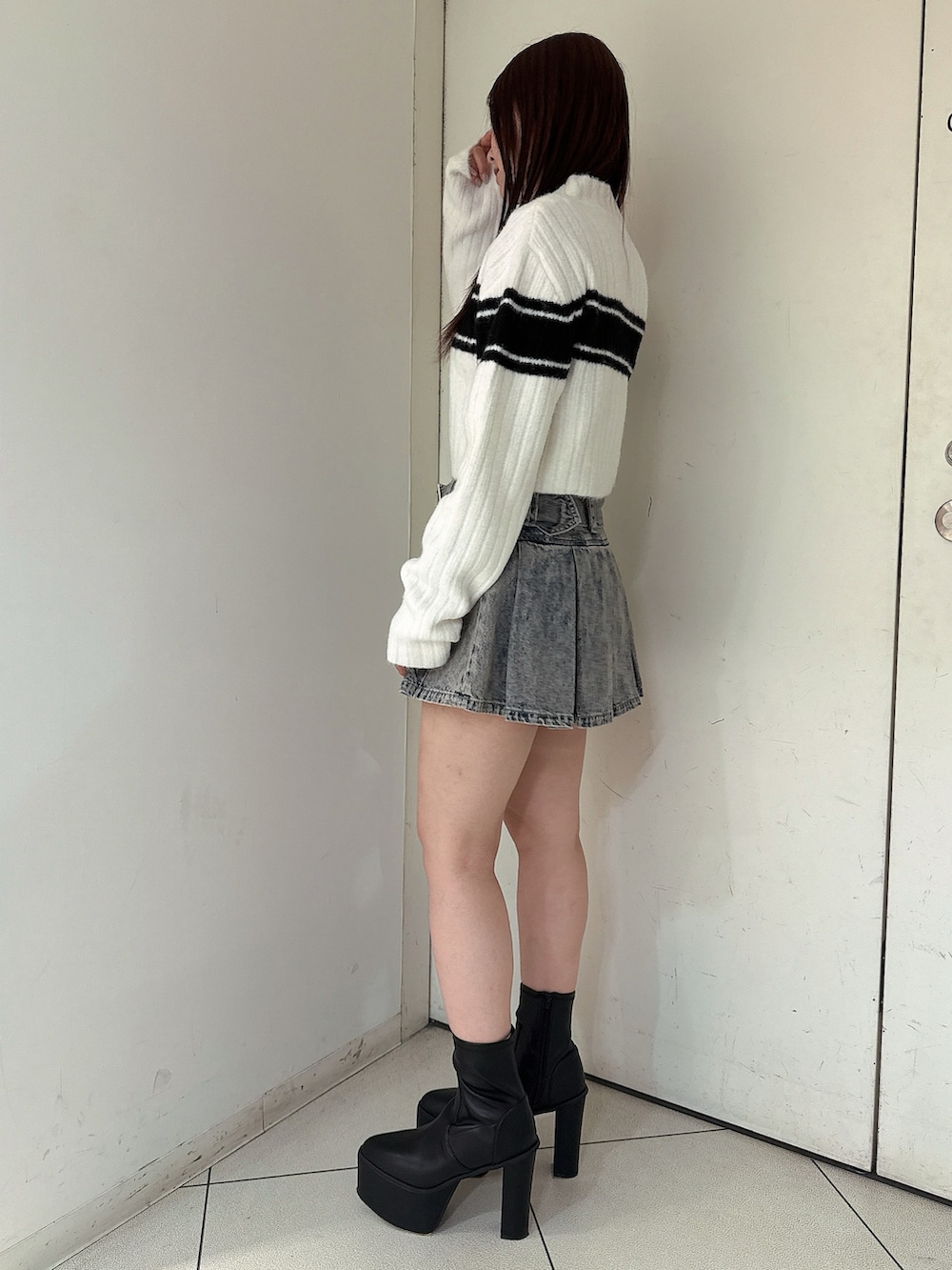 ブルー系のデニムスカート、ブラック系のブーツ、ホワイト系のニット/セーターを着用したレディースの冬コーディネートの2枚目の写真