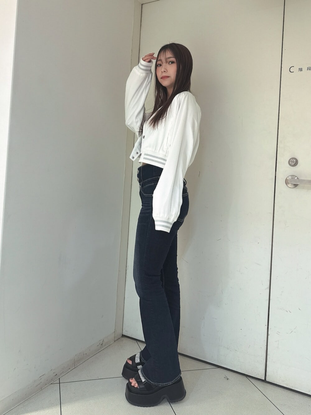 ブルー系のデニムパンツ、ブラック系のサンダル、ホワイト系のブルゾンを着用したレディースの春コーディネートの2枚目の写真