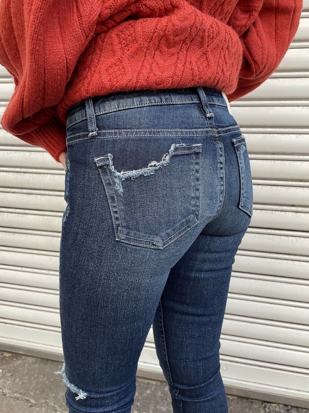 ホワイト系のブルゾン、オレンジ系のニット/セーター、ブルー系のデニムパンツを着用したレディースの秋コーディネートの7枚目の写真