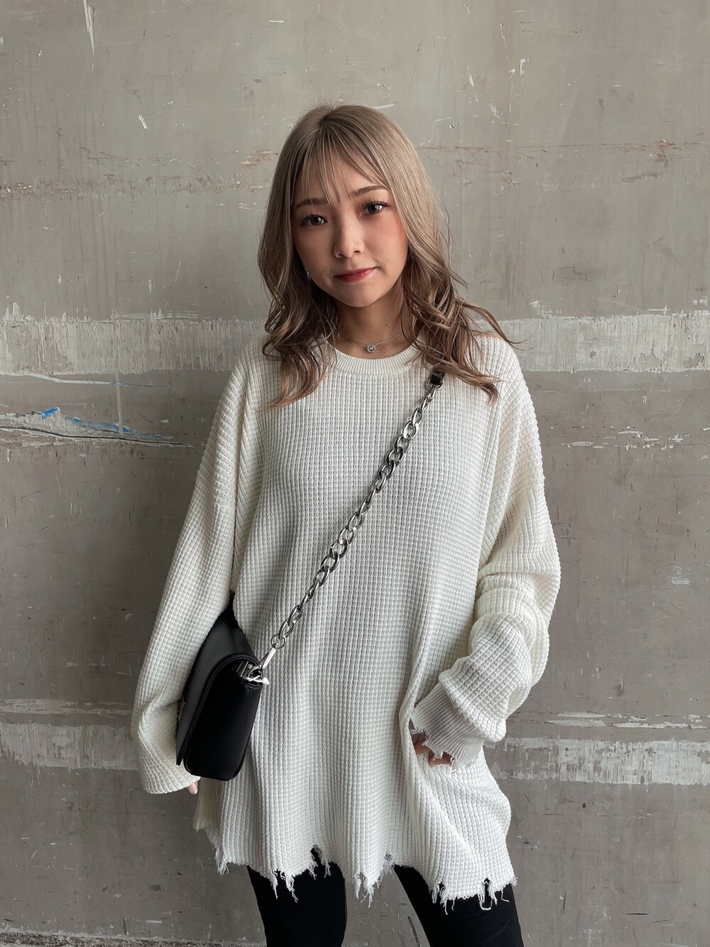 ホワイト系のニット/セーター、ブラック系のハンドバッグ、ブラック系のデニムパンツを着用したレディースの夏コーディネートの6枚目の写真