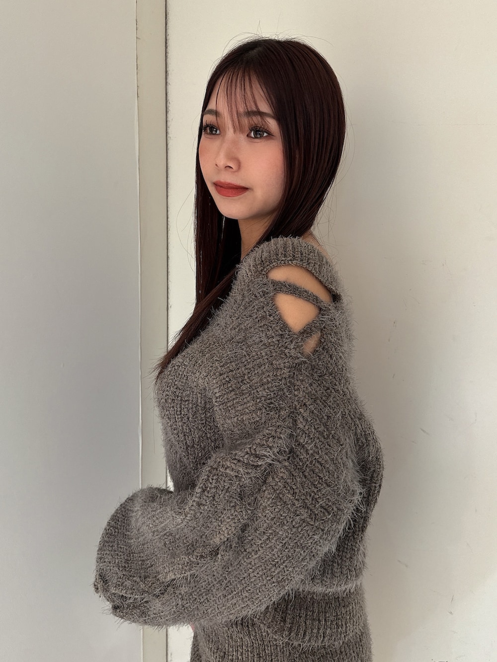 グレー系のニット/セーター、グレー系のスカート、ブラック系のブーツを着用したレディースの秋コーディネートの5枚目の写真