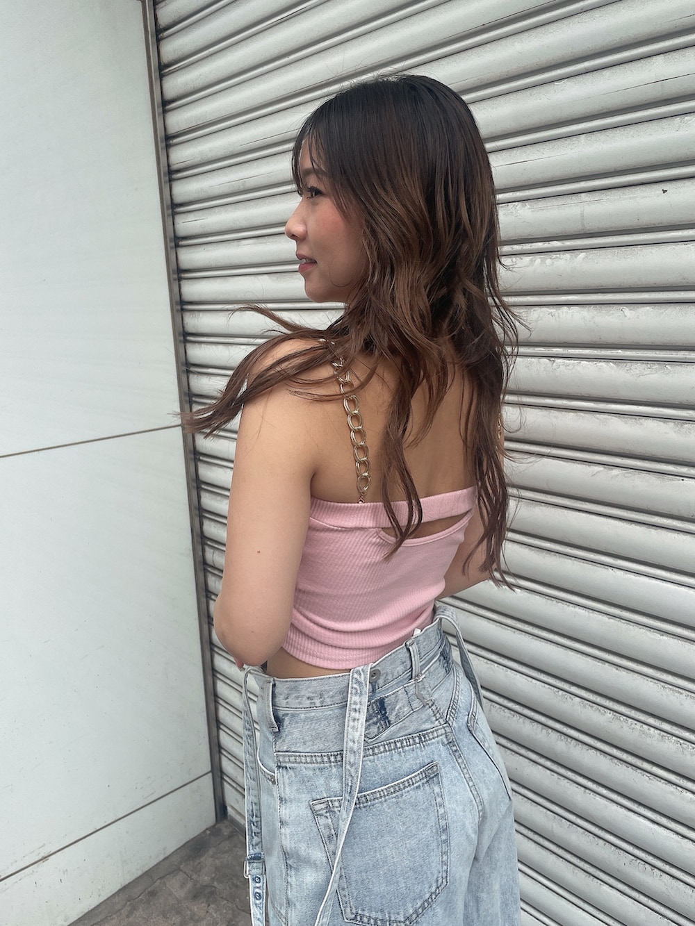 ピンク系のキャミソール、ブルー系のデニムパンツ、ホワイト系のスニーカーを着用したレディースの夏コーディネートの5枚目の写真