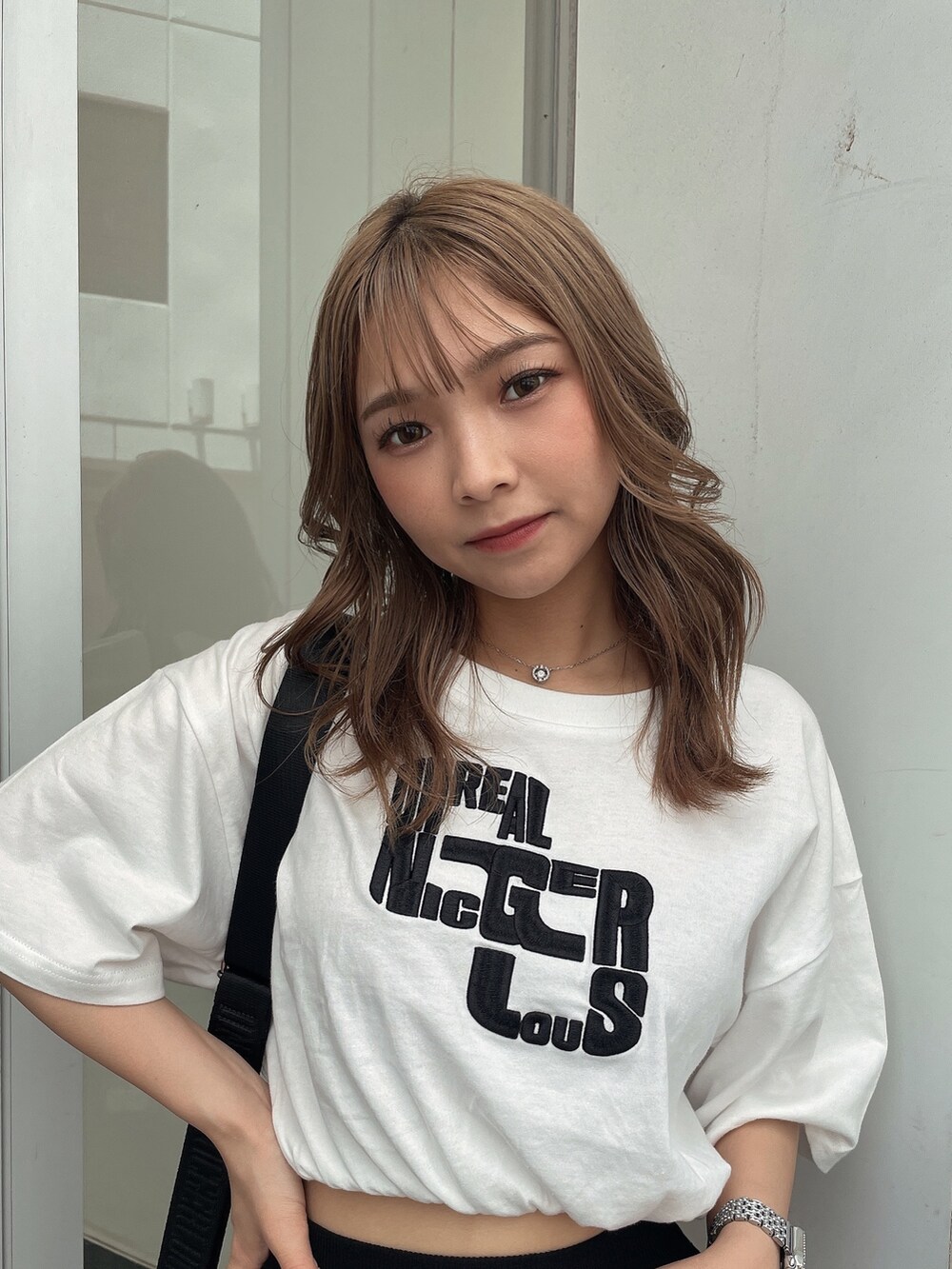 ブラック系のスカート、ブラック系のハンドバッグ、ホワイト系のTシャツ/カットソーを着用したレディースの夏コーディネートの5枚目の写真